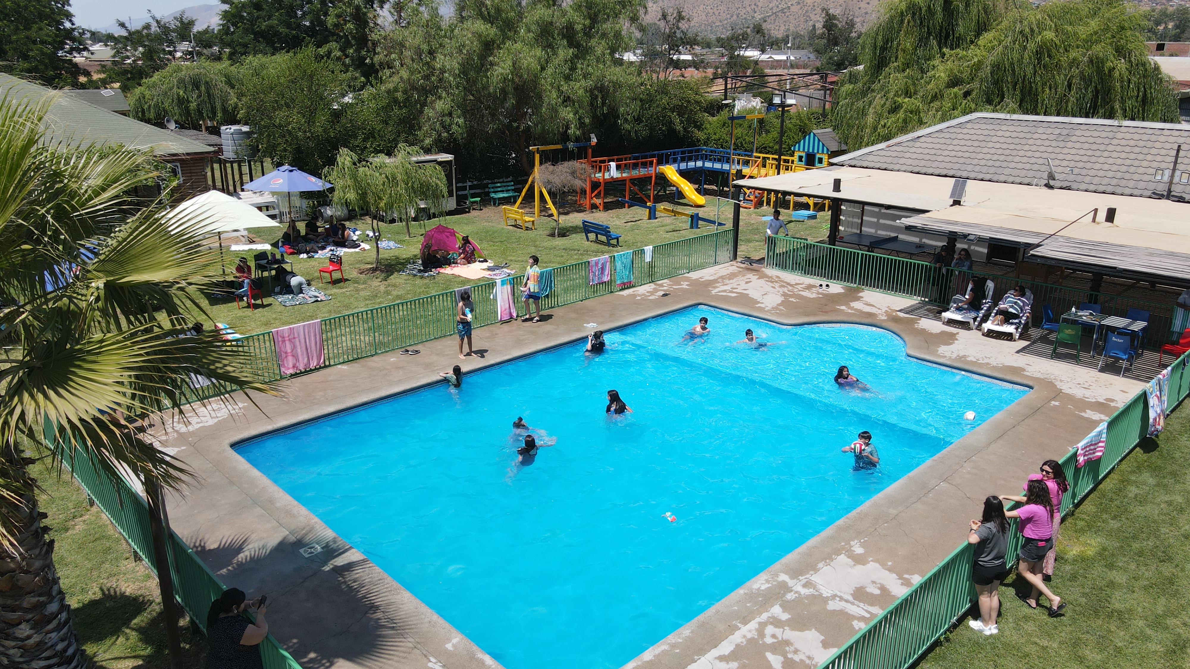 Familias disfrutando de la piscina semiolímpica de Kechuaukan, con quincho, juegos infantiles y áreas verdes al fondo